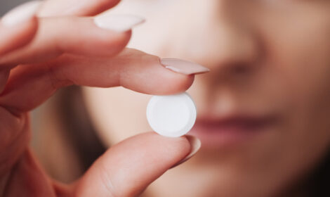 White pill in fingers. Woman holding drug. Narcotics background. Young girl taking drugs. Hand holding white tablet. Sickness and illness cure.