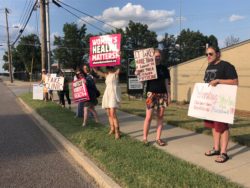 Activist protest on sidewalk outside a fake clinic in Columbia MO, holding signs with information about medication abortion and repro justice