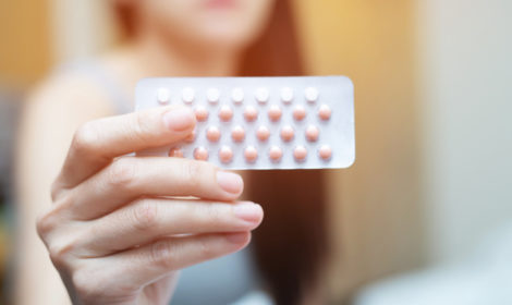 Woman hands opening birth control pills in hand