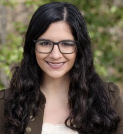Headshot of Shireen Shakouri, woman with long dark hair and glasses against a green background