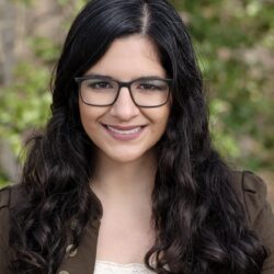 Headshot of Shireen Shakouri, woman with long dark hair and glasses against a green background