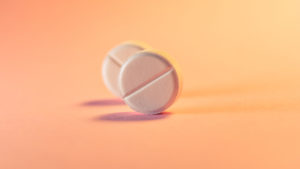 Two pills in an orange-pink background. Medical theme. Selective focus.