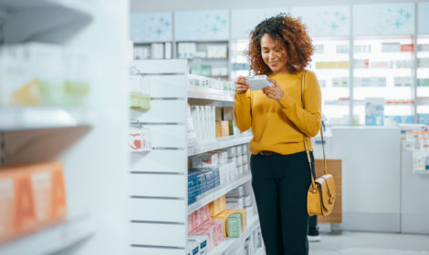 Pharmacy Drugstore: Beautiful Black Young Woman Walking Between Aisles and Shelves Shopping for Medicine, Drugs, Vitamins, Supplements, Health Care Beauty Products with Modern Package Design